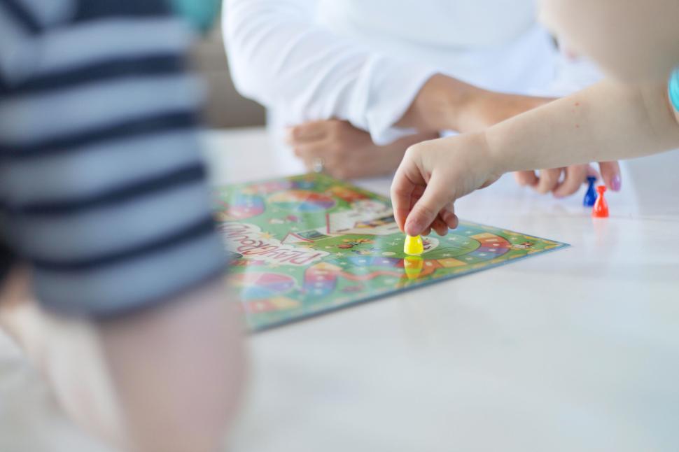 Free Image of People playing a colorful board game together around a white table 