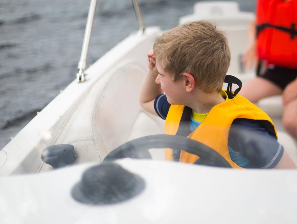 Free Image of Young boy steering a boat and navigating on a clear sunny day 