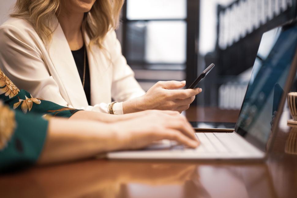 Free Image of Two women working together on a laptop and smartphone in an office 