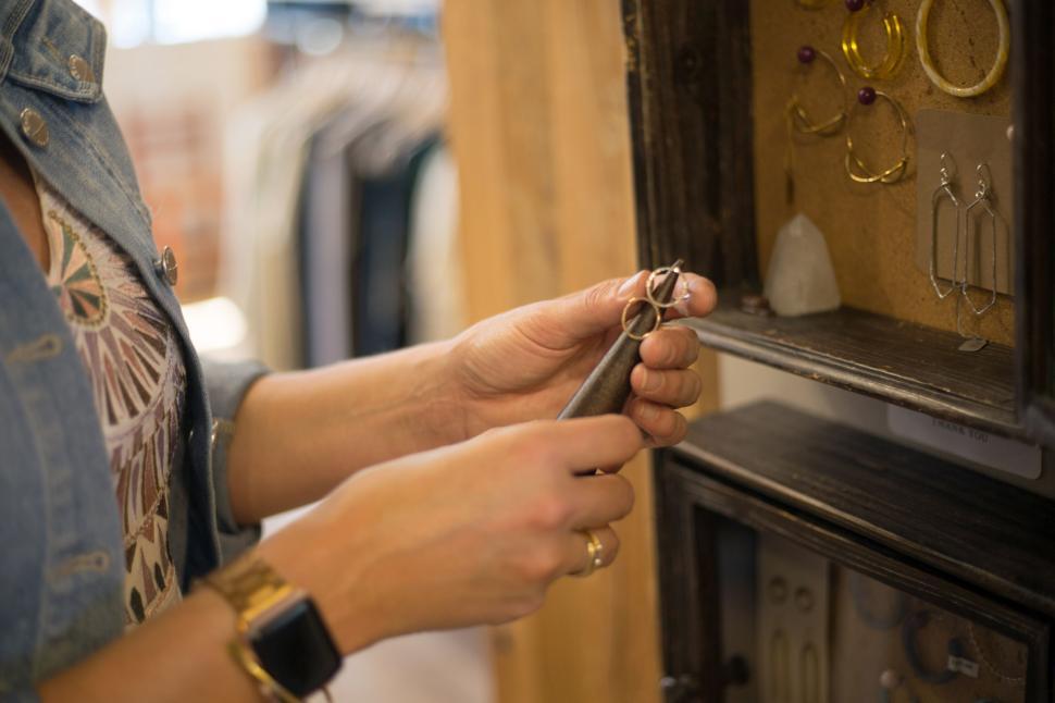 Free Image of Woman examining jewelry with precision tools in a boutique setting. 