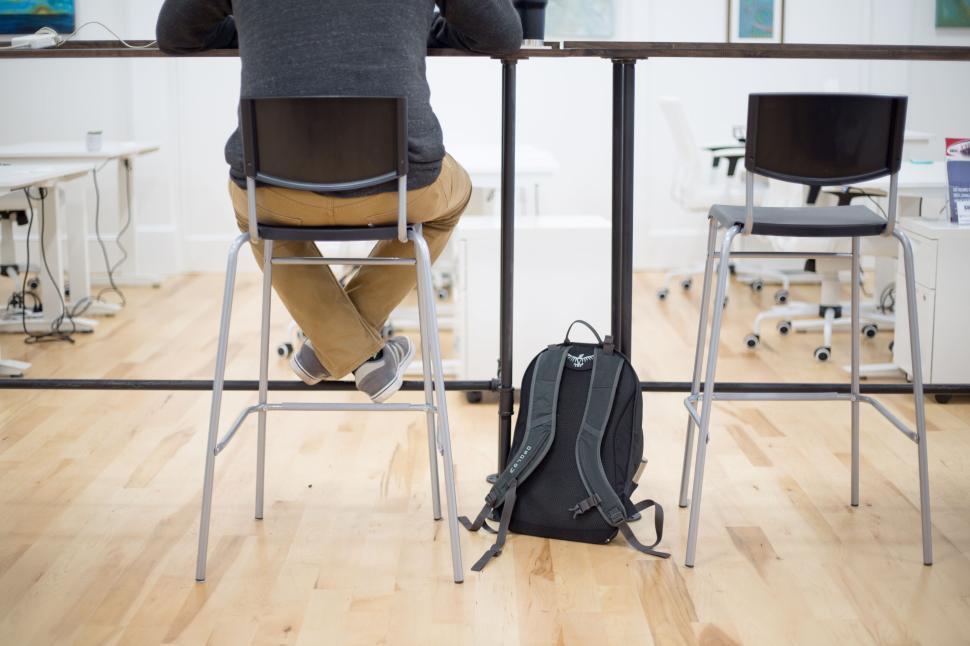 Free Image of Person working at a high table in a modern, open office space. 