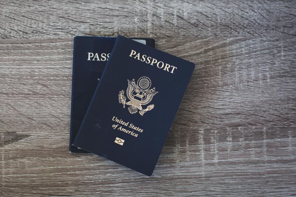Free Image of Two US passports on wooden surface, ready for international travel 