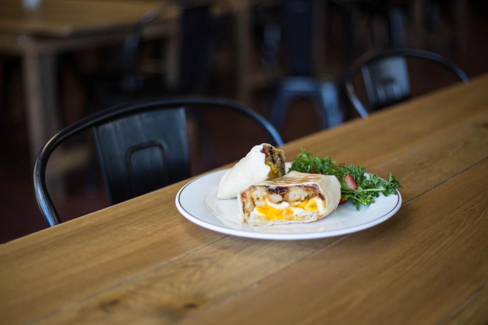 Free Image of Delicious breakfast burrito with side salad on wooden table 