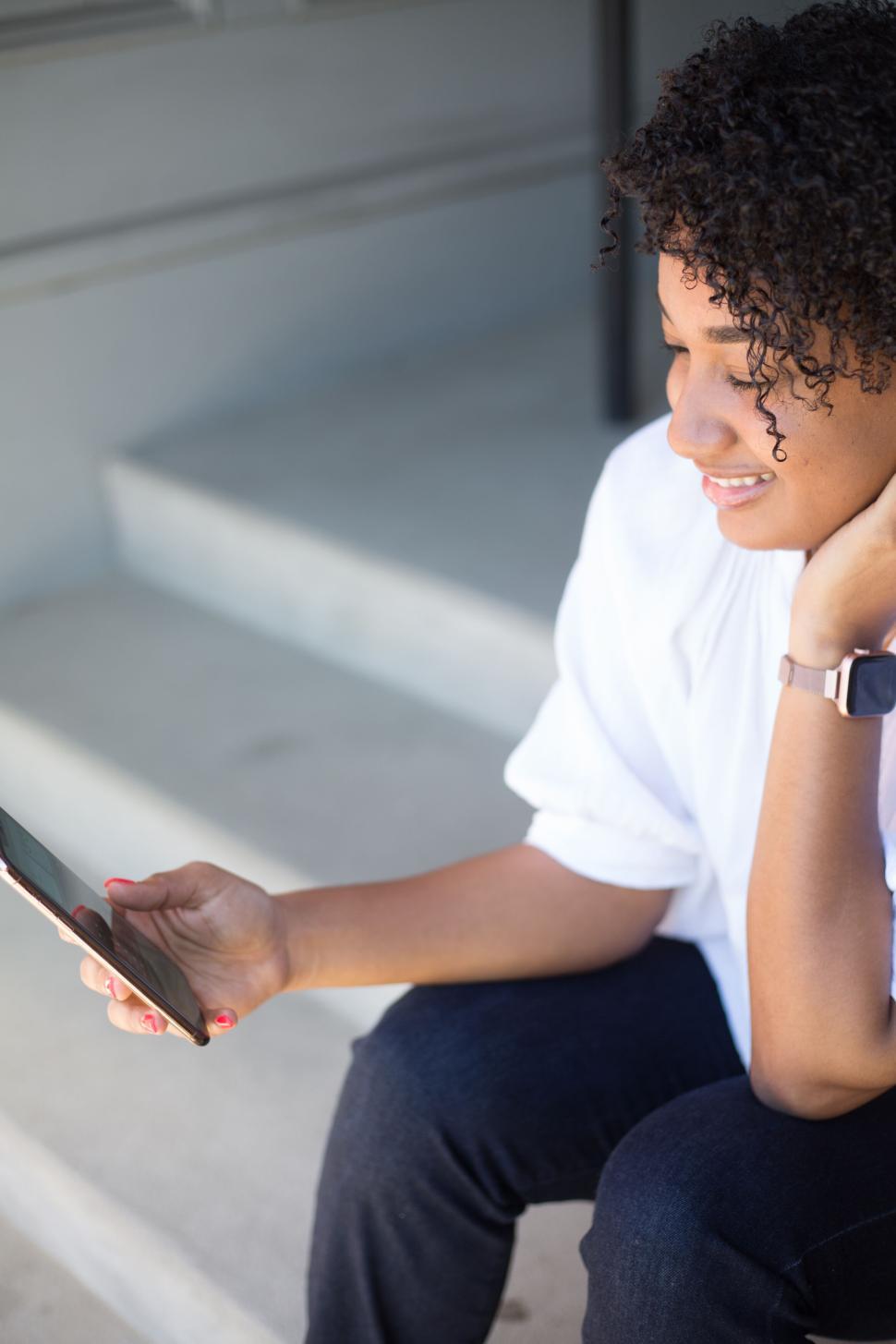 Free Image of Woman checking her phone while sitting on concrete stairs 