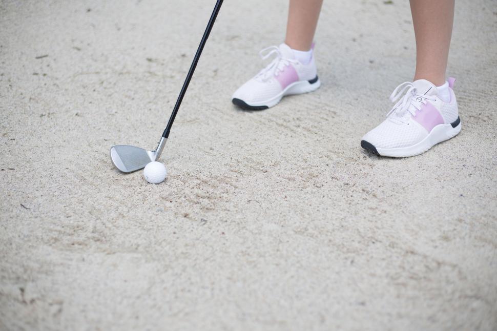 Free Image of Golfer with club and ball on sandy course during a match practice. 