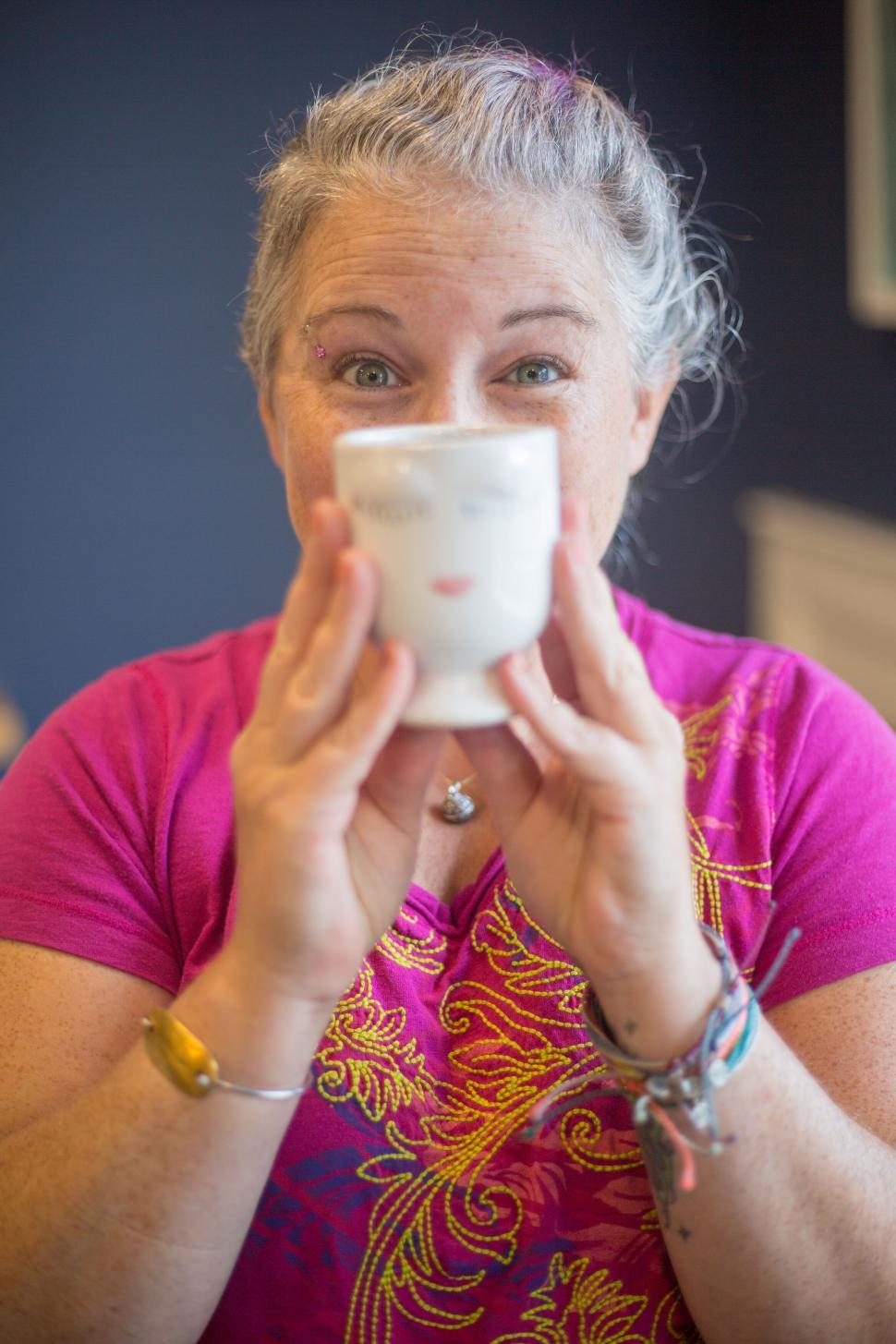 Free Image of Woman enjoying a cup of tea in vibrant attire in a casual setting. 