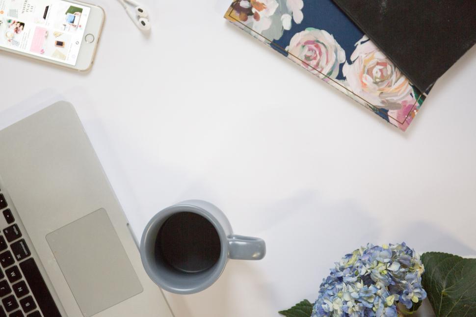 Free Image of Laptop and coffee on a white table beside floral-themed notebooks 
