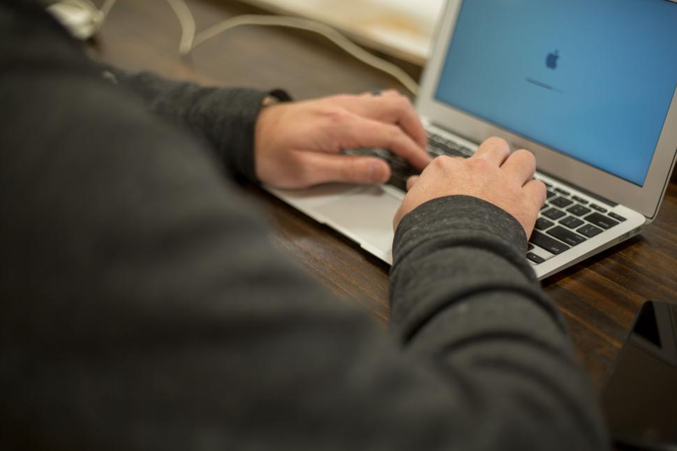 Free Image of Person typing on a laptop in a professional workspace setting 