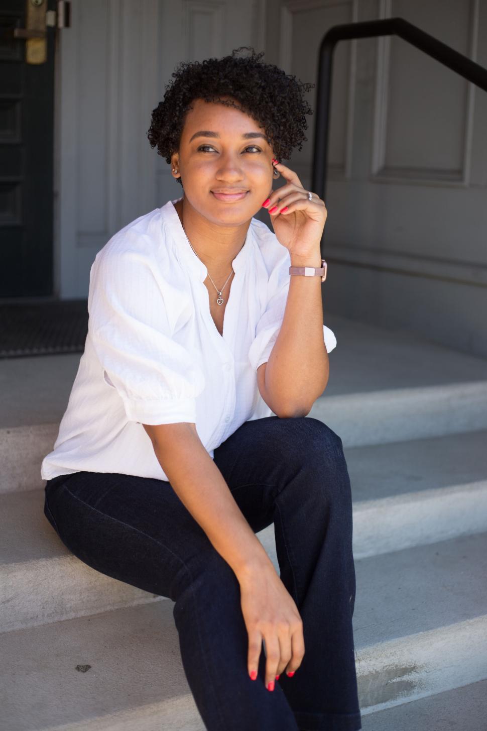 Free Image of Content woman with short curly hair, sitting on outdoor steps. 