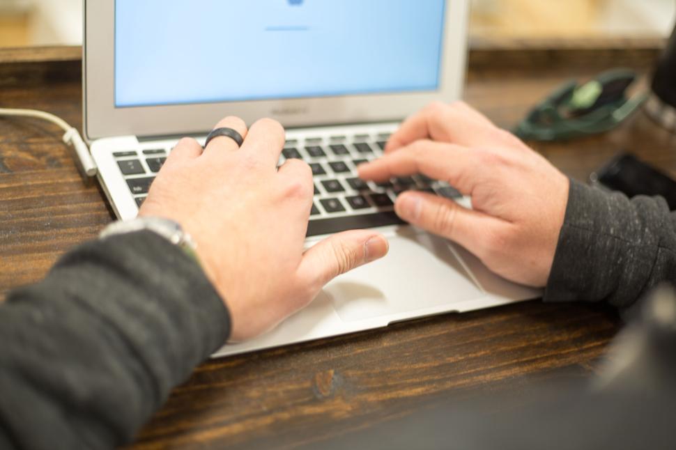 Free Image of Close-up shot of hands typing on a MacBook keyboard. 