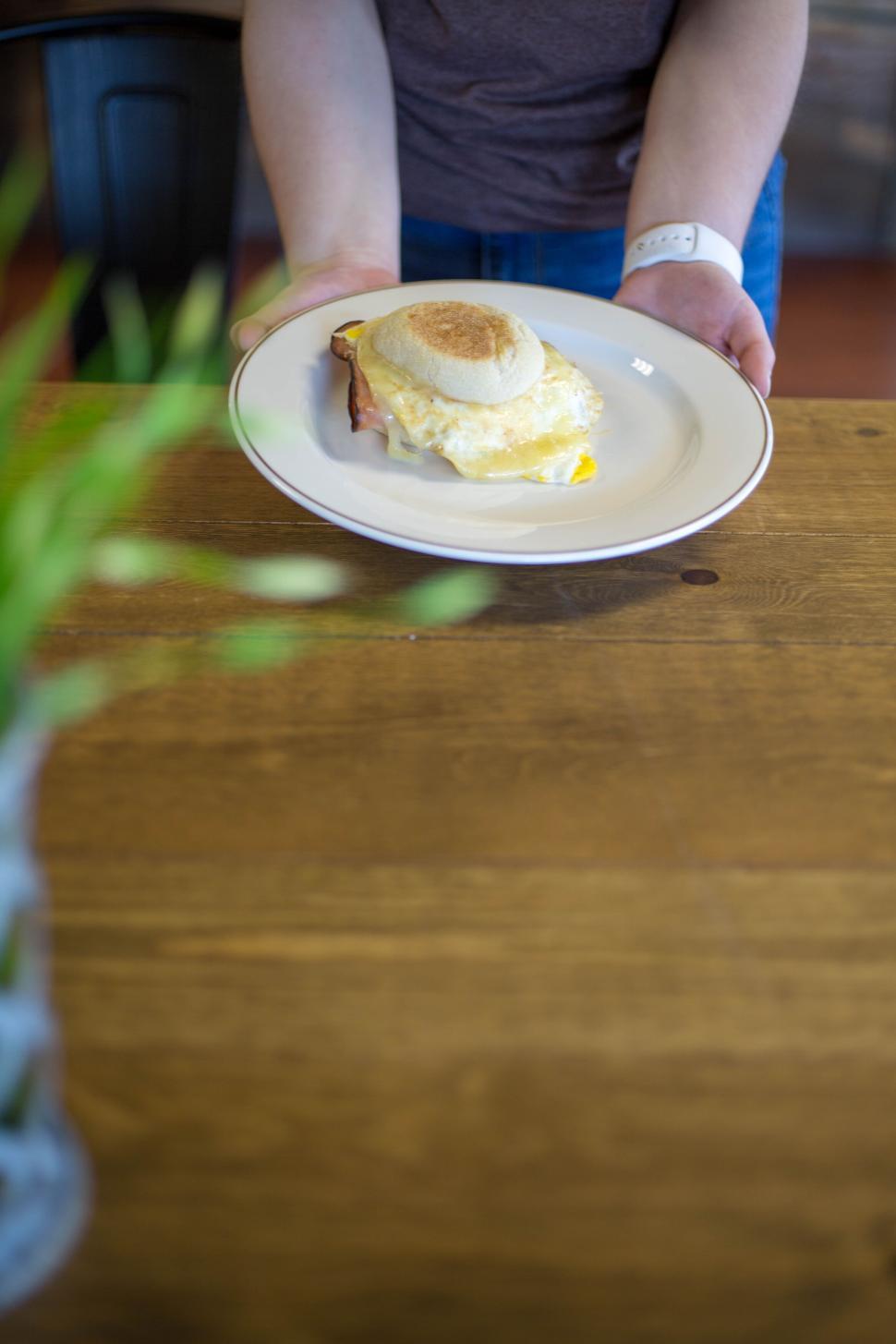 Free Image of Plate with a sandwich presented on a wooden table in a cafe. 