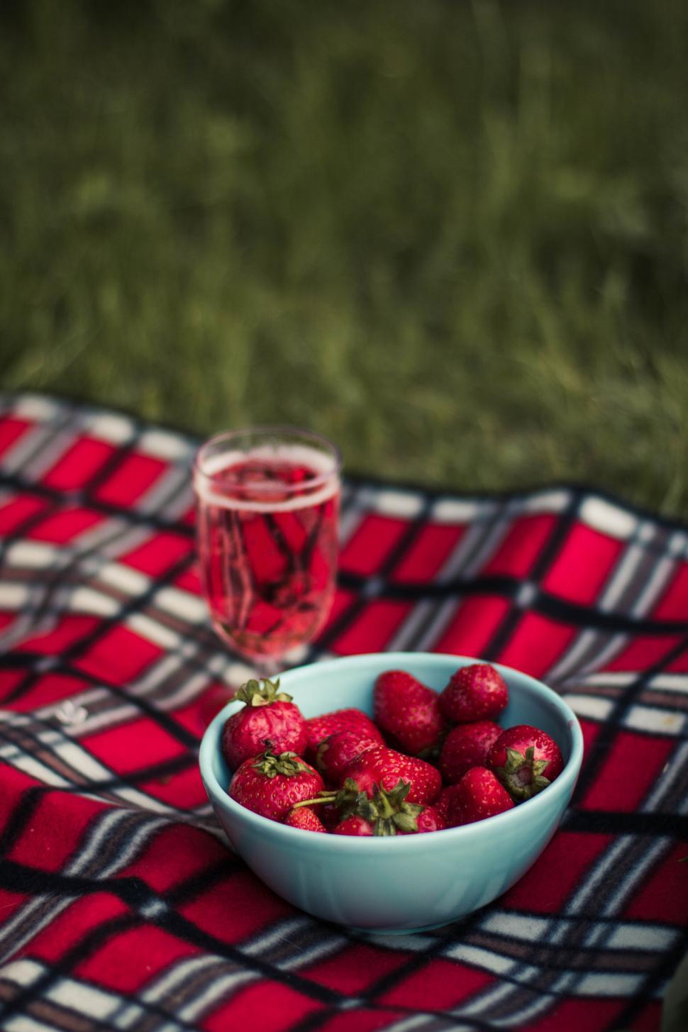 Free Image of Picnic setup with a bowl of strawberries and sparkling drink. 