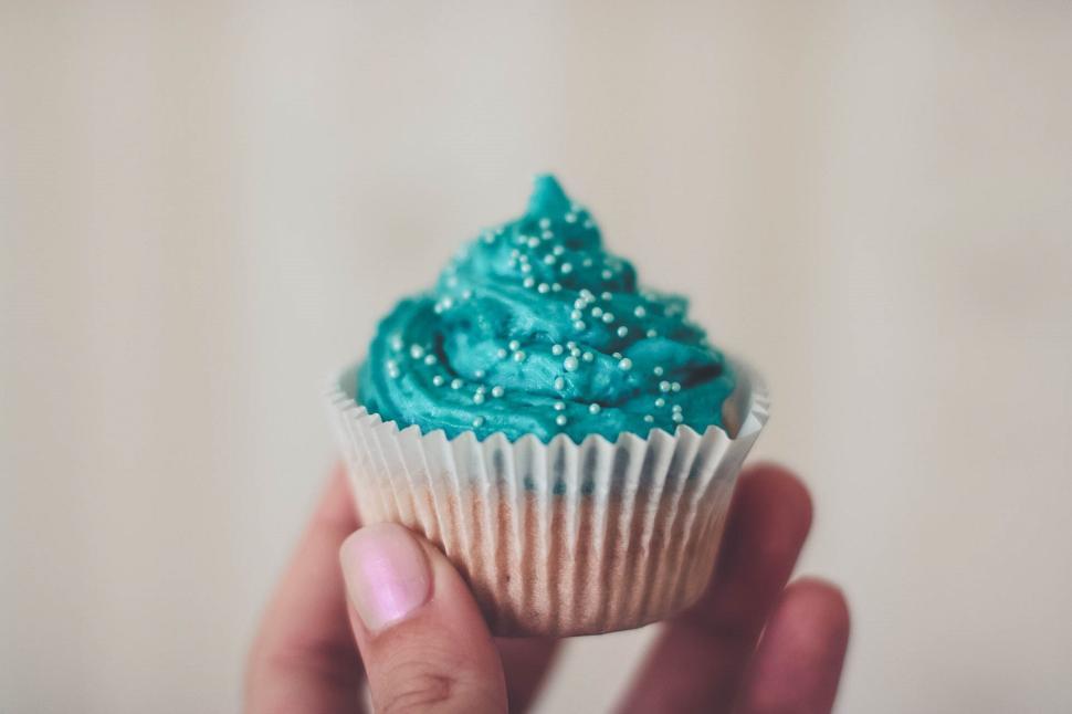 Free Image of Cupcake with turquoise frosting and small white sprinkle details. 