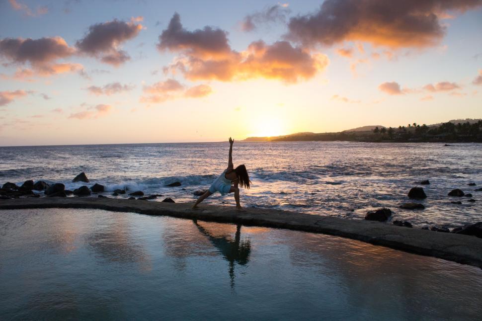 Free Image of Elegant woman practicing yoga by the ocean during a stunning sunset 