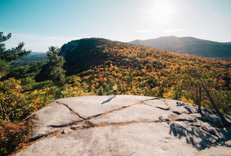 Free Image of Hiker on a mountain peak with a vast landscape and bright sky 