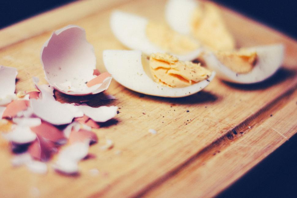 Free Image of Hard-boiled eggs cut in half with shells scattered on a board. 