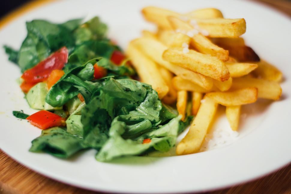Free Image of Fresh garden salad served with crispy golden French fries on a plate. 