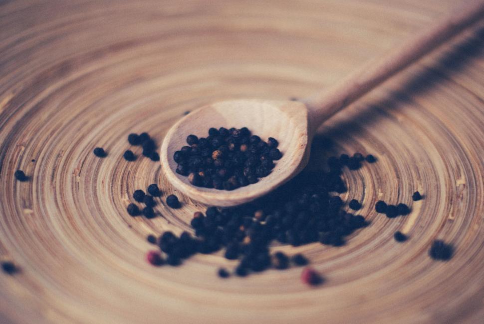 Free Image of Wooden spoon holding black peppercorns in a rustic setting. 