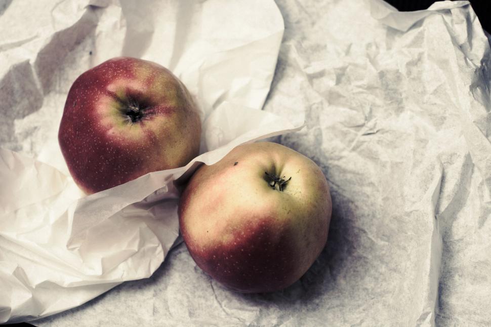 Free Image of Two fresh apples wrapped in white paper, displayed on table. 
