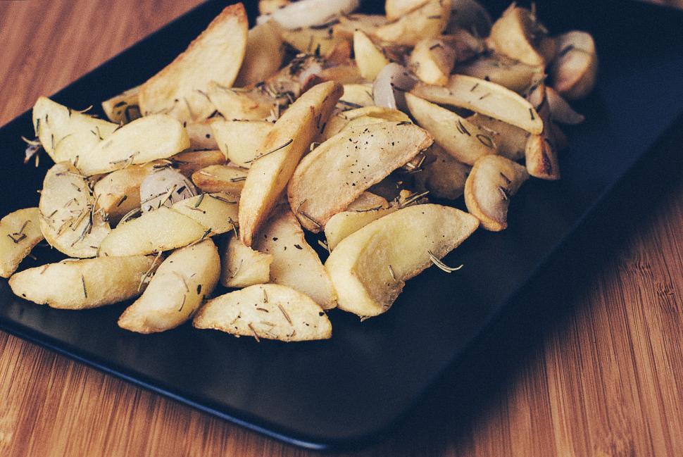Free Image of Appetizing seasoned potato wedges on a black rectangular serving tray 