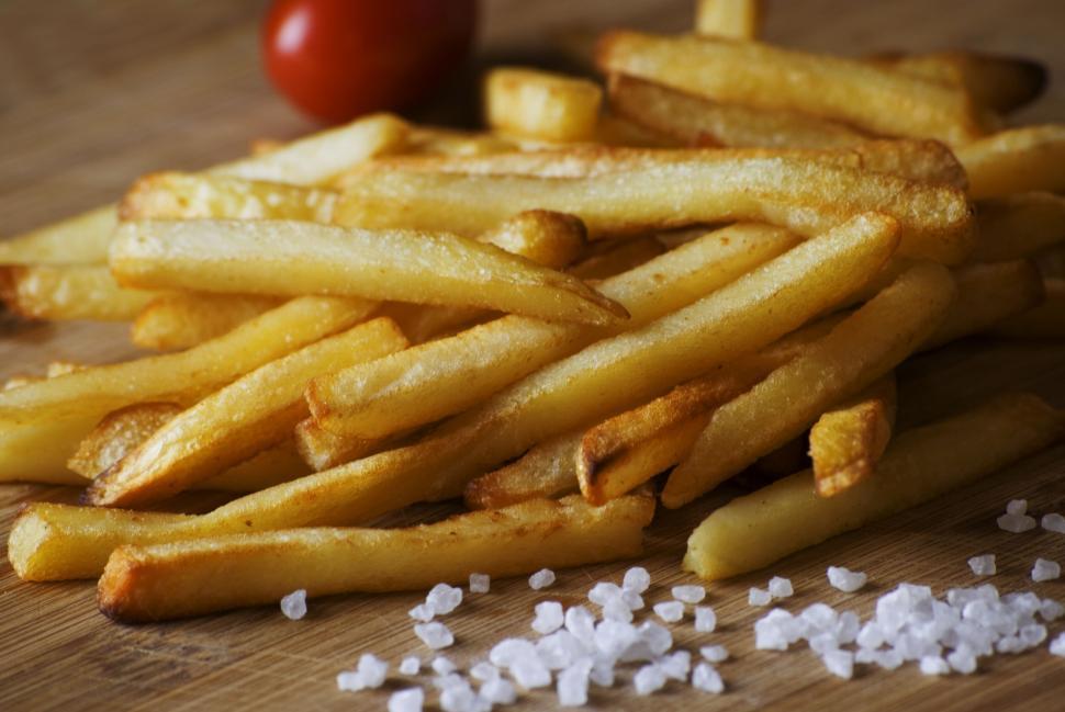 Free Image of A heap of crispy French fries seasoned with sea salt on wood table. 