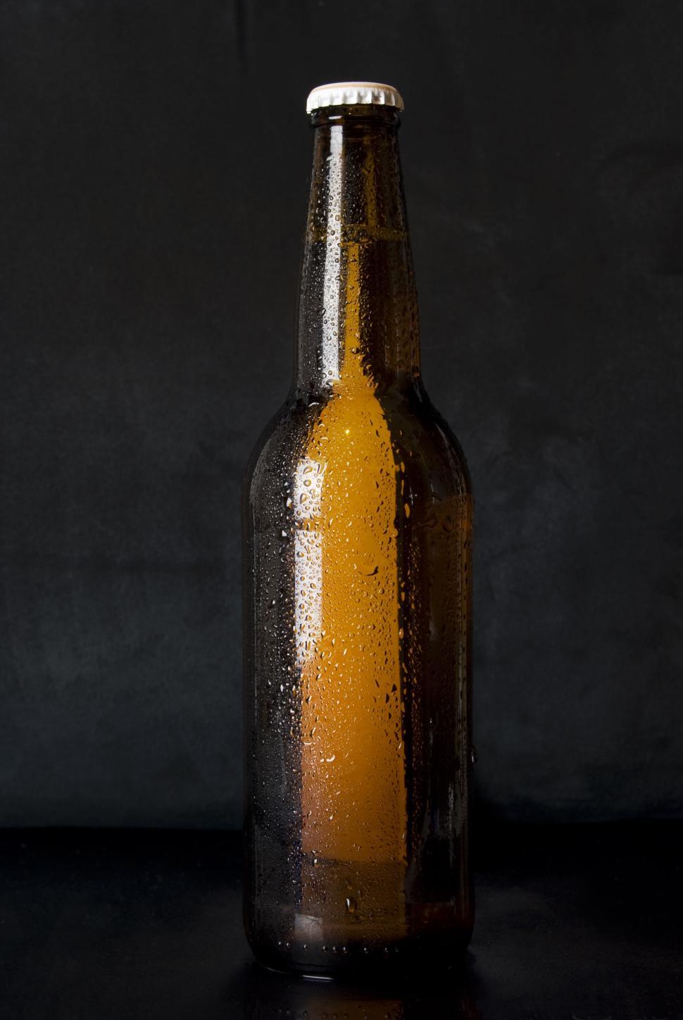 Free Image of Chilled amber beer bottle with condensation against a dark background 