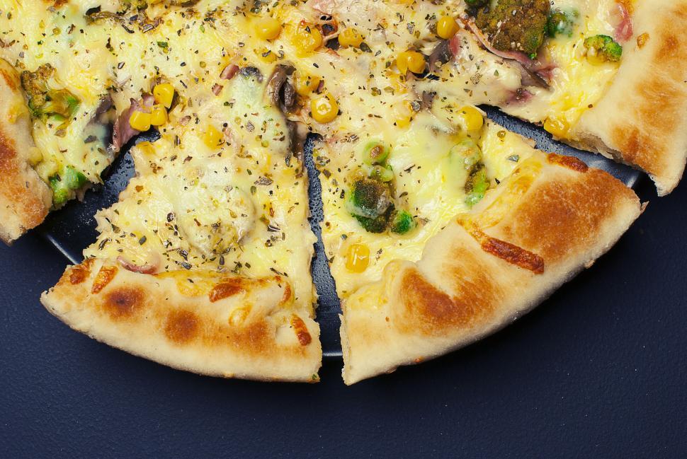 Free Image of Cheesy pizza slice with toppings on a pizza plate close-up view 