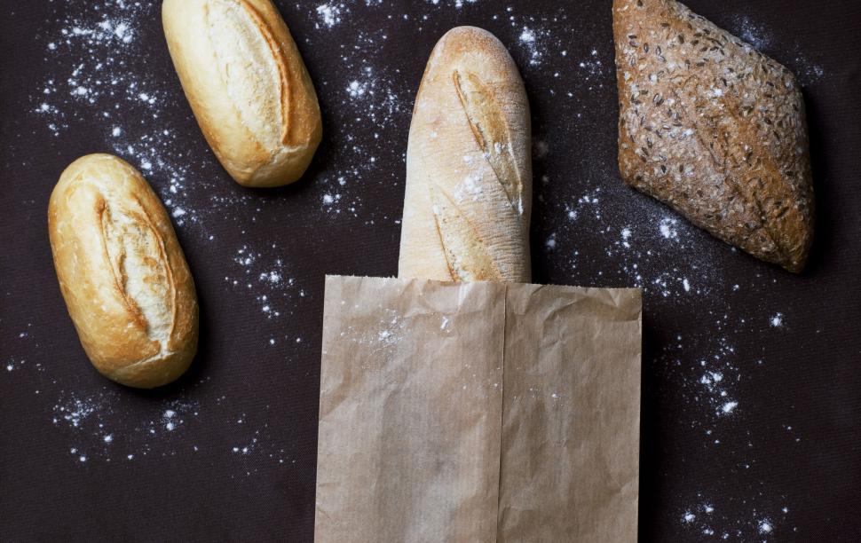 Free Image of Variety of freshly baked bread loaves with flour on a dark surface. 