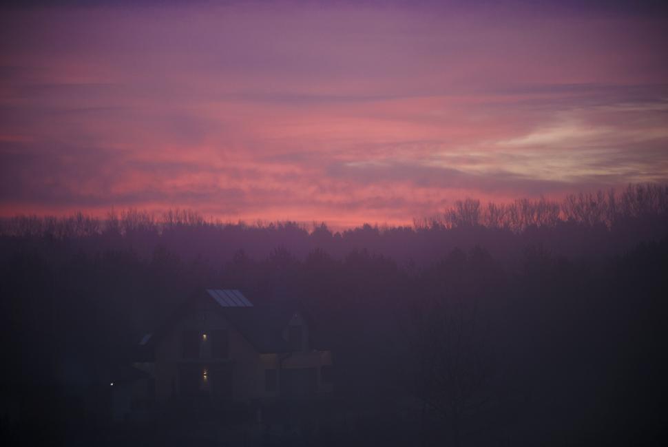 Free Image of House silhouette at colorful sunset with trees on misty evening 