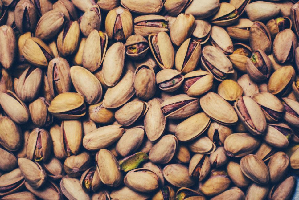Free Image of Pile of unshelled pistachios in a cozy and rustic food setting 