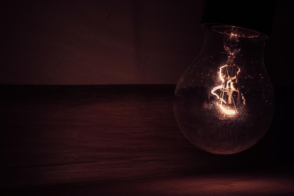 Free Image of Dimly lit incandescent light bulb glowing in the dark atmospheric room. 