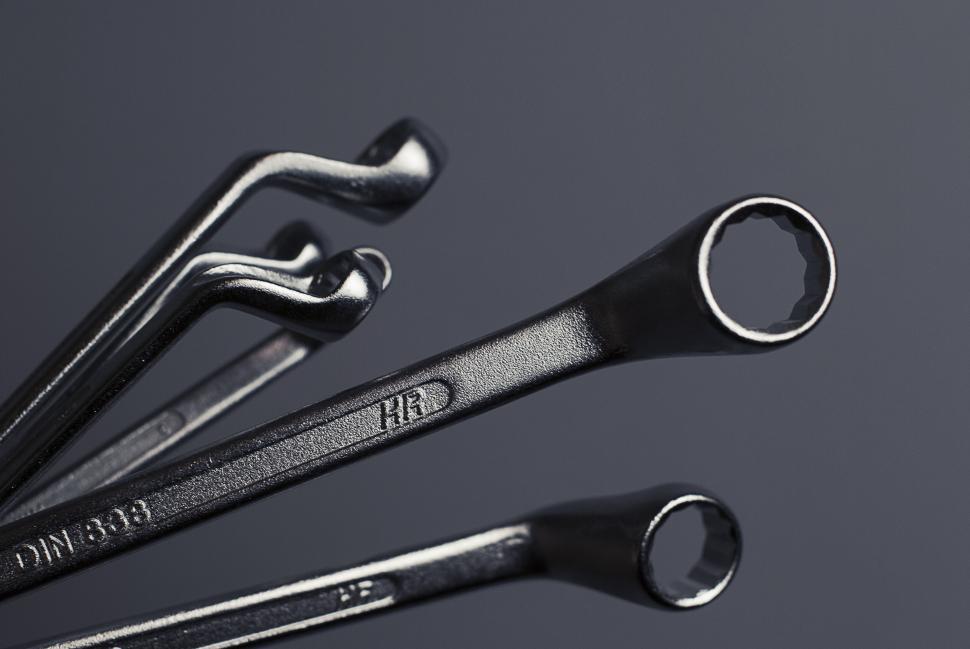 Free Image of Set of metallic wrenches neatly arranged against a minimalistic backdrop. 