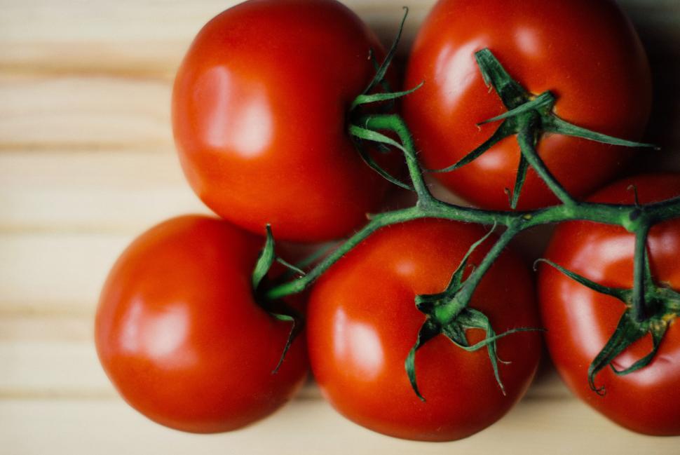Free Image of Five ripe red tomatoes on a light wooden surface showcase freshness 