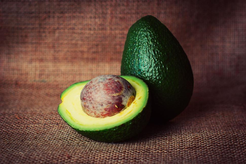 Free Image of Whole and halved avocado on burlap background showcase green texture 