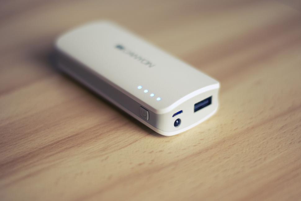 Free Image of Portable white power bank with LED indicators on wooden surface. 