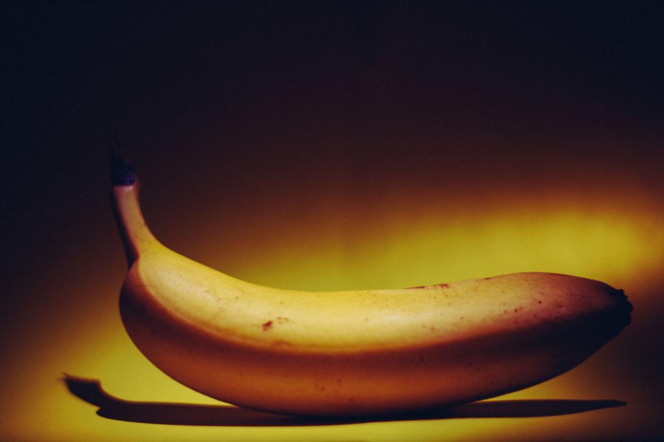Free Image of Single ripe banana on dark, dramatic background with yellow light. 