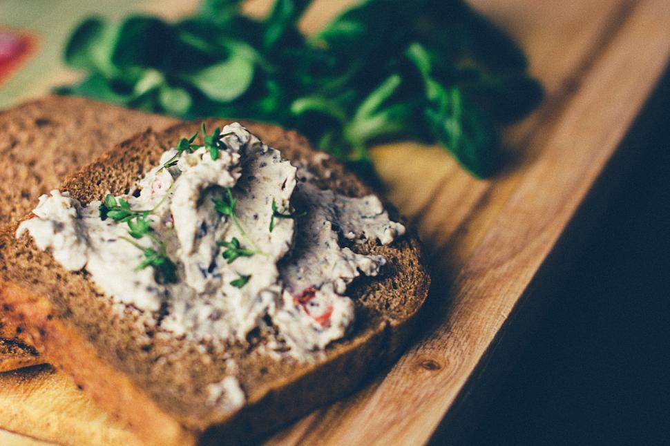 Free Image of Slices of brown bread topped with creamy spread and fresh herbs. 