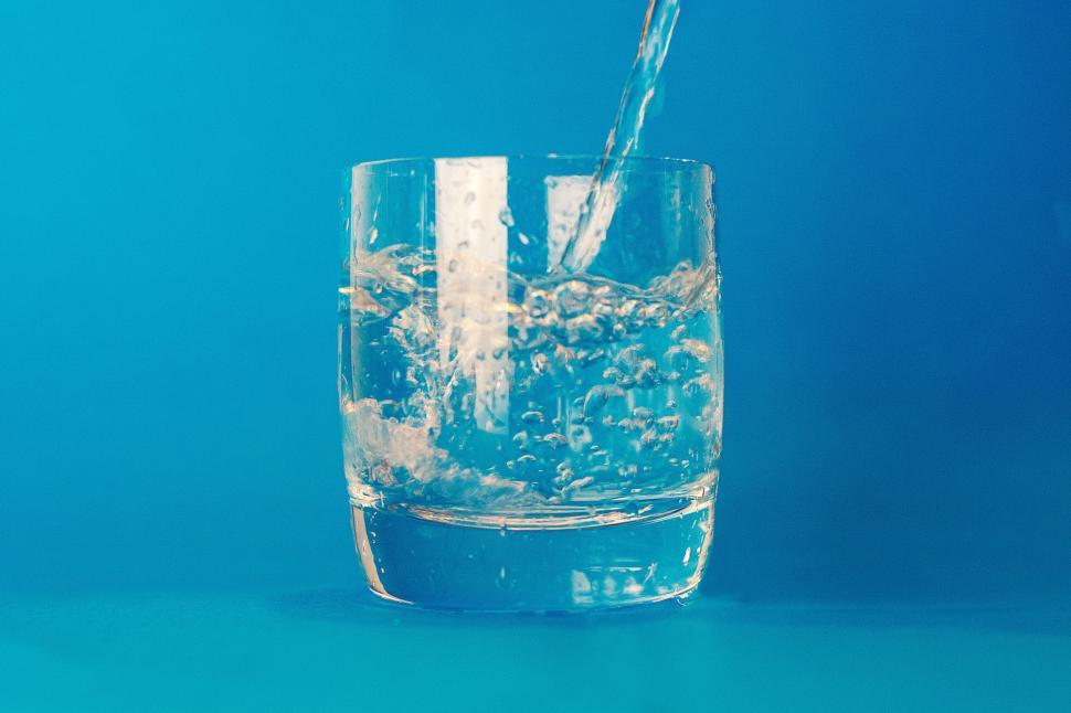 Free Image of Clear glass being filled with refreshing water on blue background. 