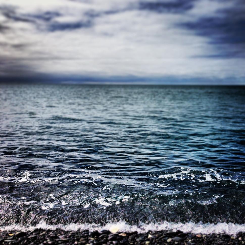 Free Image of Calm ocean waves gently lapping against a pebble beach shore 