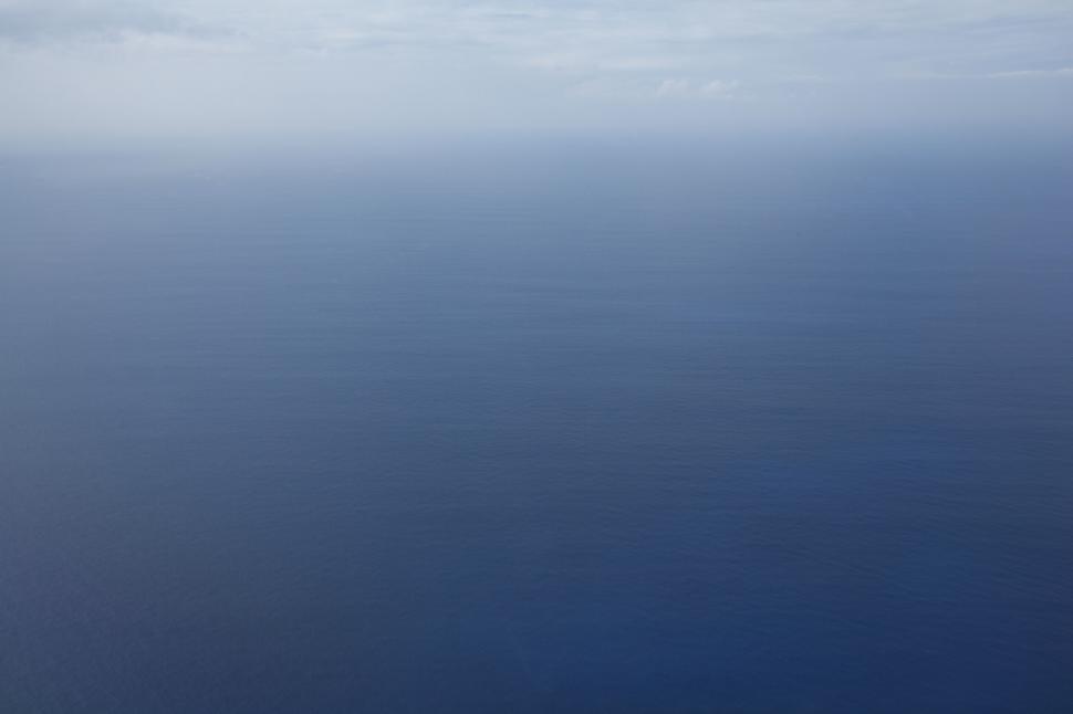 Free Image of Open expanse of calm, blue ocean under a clear, expansive sky 