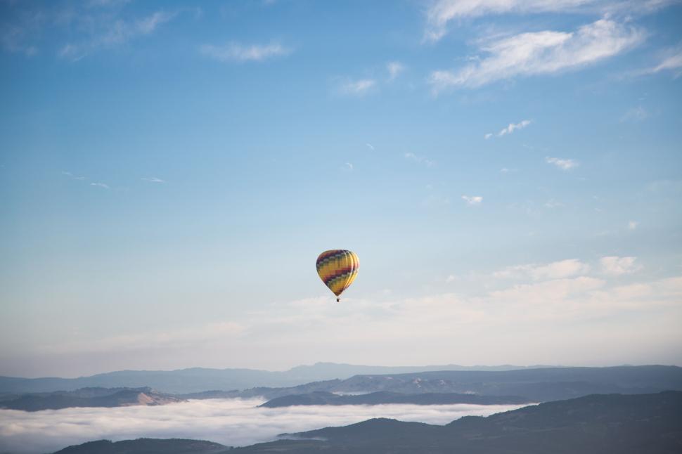 Free Image of Hot air balloon floating high over a misty, mountainous landscape 