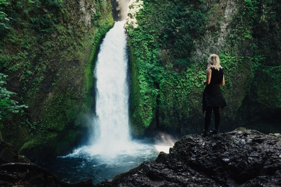 Free Image of Person standing near waterfall in lush green forest surroundings 