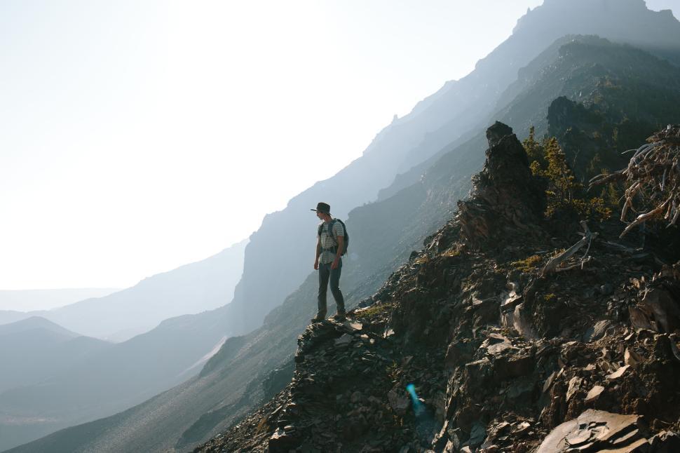 Free Image of Adventurous hiker standing on a rocky mountain peak at sunrise 