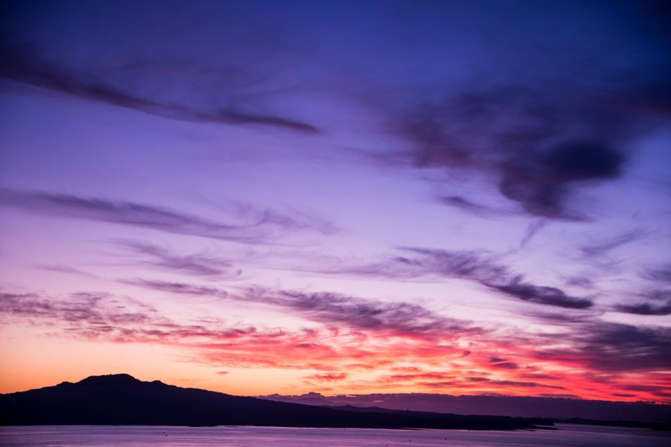 Free Image of Vibrant sunset over the ocean with colorful clouds and sky s hues 
