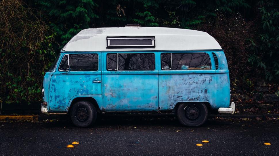 Free Image of Old blue and white van parked beside trees on an overcast day 