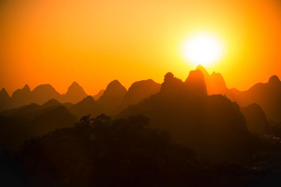 Free Image of Sunset over silhouette of rugged mountain range and golden sky. 