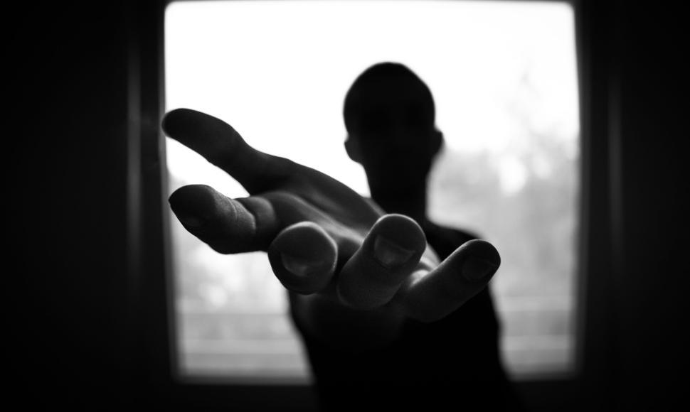 Free Image of Person reaching out a hand in black and white with window behind 