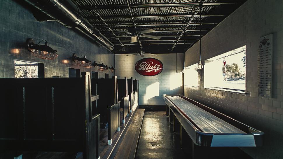 Free Image of Empty restaurant interior with wooden booths and a shuffleboard table. 