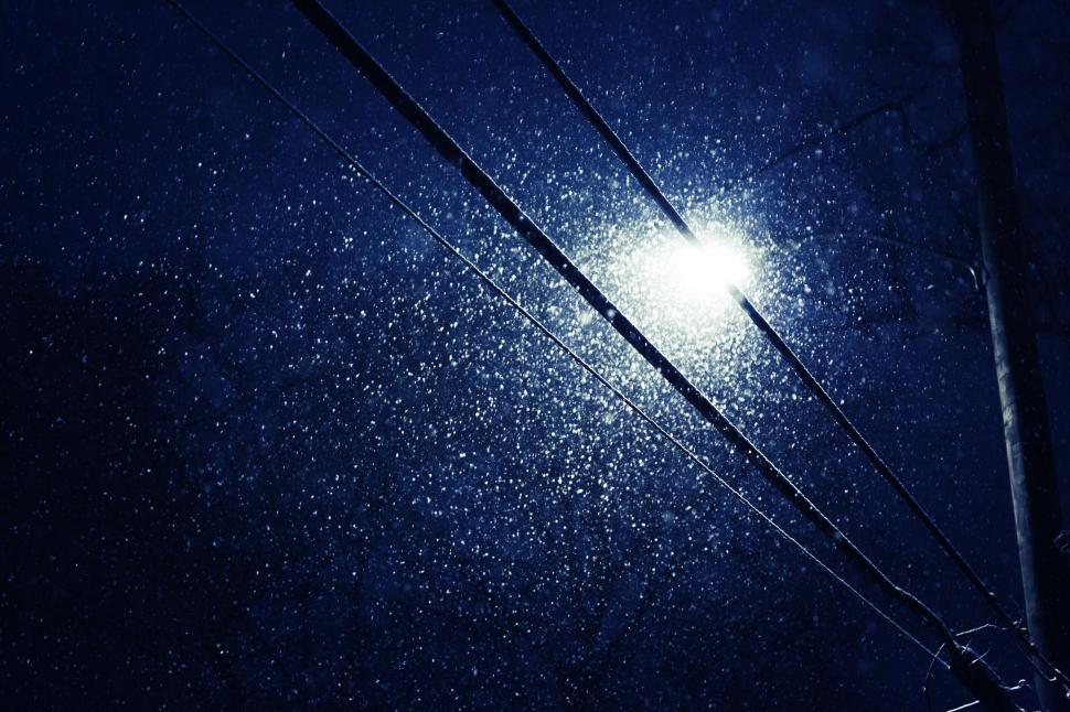 Free Image of Snow falling at night with a street light illuminating the snowflakes. 