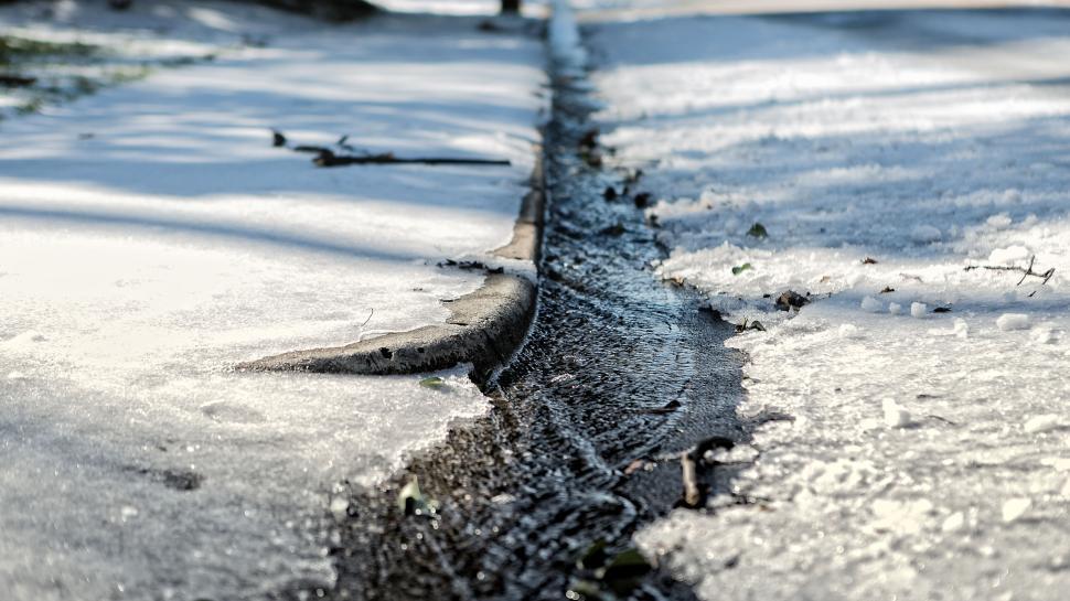 Free Image of Snowy and icy curbside with a flowing stream 